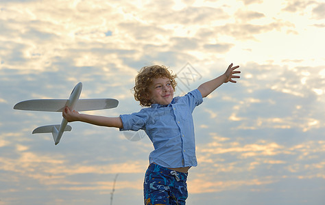 飞机梦小男孩田野上着个木制的飞机模型背景