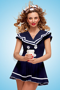 张趣的女水手带着咖啡杯的创意照片,她的头发上蓝色背景的风图片