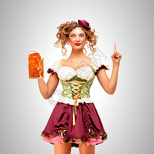 漂亮的啤酒节女服务员穿着传统的巴伐利亚连衣裙,戴着个啤酒杯,灰色的背景上想出了个主意图片