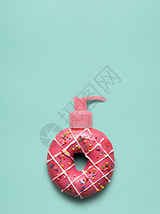 创意静物的美味甜甜甜圈与化妆品泵分配器蓝色背景图片