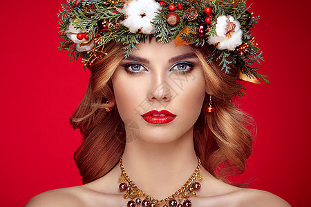 带诞花环的美丽轻女人的肖像美丽的新诞树假日发型化妆美女肖像孤立红色背景上五颜六色的妆容头发图片
