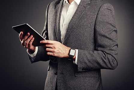 穿着西装的英俊轻人休闲风格电子设备智能手表数字平板电脑图片