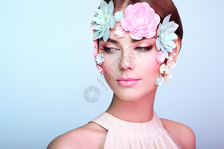 用花装饰的美丽女人的脸完美的妆容美丽时尚模特女人完美的皮肤纸花背景图片