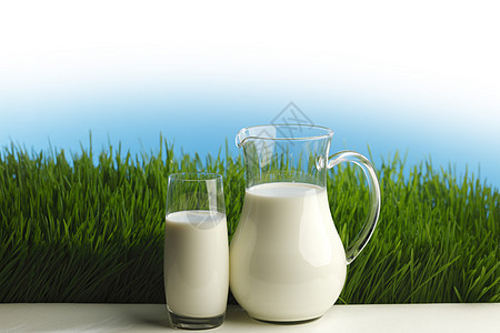 新鲜草地上的杯牛奶罐子图片