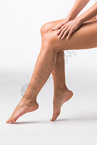 漂亮的女腿美丽的女腿白色背景上用手触摸图片