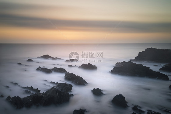 惊人的长曝光景观图像的海洋岩石上,充满活力的日落图片