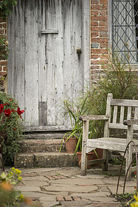 美丽的典型的旧英国乡村花园形象木制椅子旁边的老式后门图片