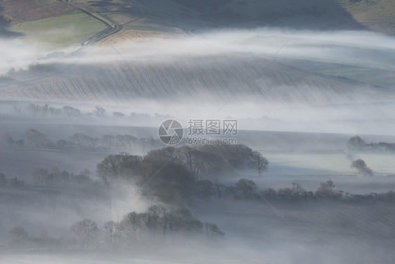 美丽的雾状英国乡村景观日出冬天,层层滚动田野图片