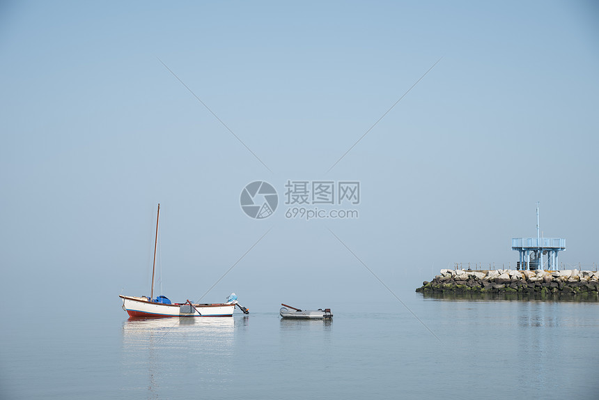 极简主义艺术景观形象的孤舟岩石极简主义的艺术形象,孤独的划船船岩石露头与救生员塔雾蒙蒙的晨光图片