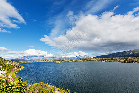 平静的景色加大的山湖旁边,岩石平静的水中反射图片