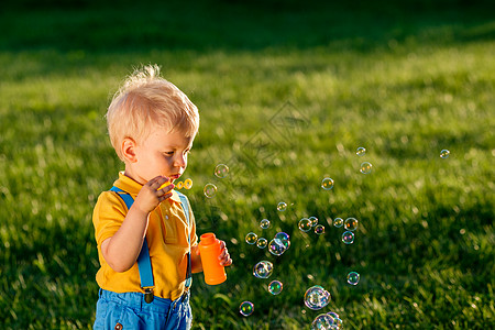 小孩绿色小男孩肥皂泡在草地上背景