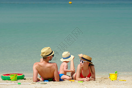 海滩上的家人两岁的蹒跚学步的男孩父母海滩上玩海滩玩具图片