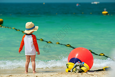 两岁的蹒跚学步的男孩戴着太阳帽海滩上散步图片