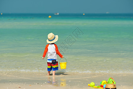 两岁的蹒跚学步的孩子海滩上玩耍两岁的蹒跚学步的男孩海滩上玩海滩玩具图片