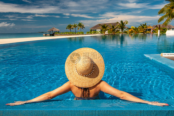 马尔代夫海滩游泳池戴帽子的女人马尔代夫海滩泳池里戴着太阳帽的女人图片