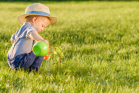 幼儿户外岁的小男孩戴着草帽,用浇水罐户外幼儿的肖像农村场景岁小男孩戴草帽用浇水罐图片