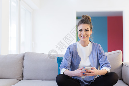 轻快乐的女人豪华的家里用手机沙发上图片