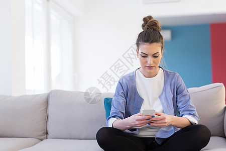 轻快乐的女人豪华的家里用手机沙发上图片