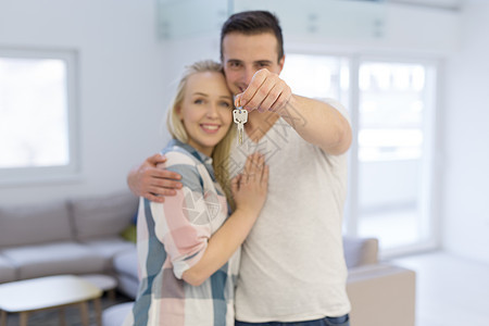 幸福微笑的轻夫妇拥抱,同时展示他们的新房子的钥匙图片