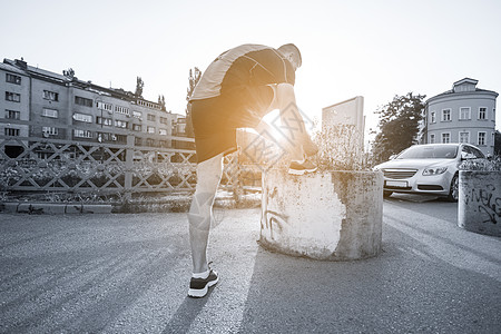 男人系着跑鞋鞋带,准备阳光明媚的早晨城市里跑步图片