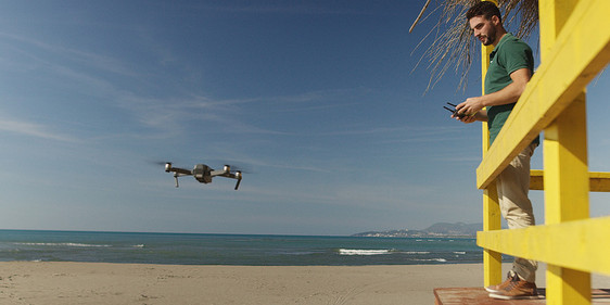 秋天的天,人们海边用遥控机操作无人机图片