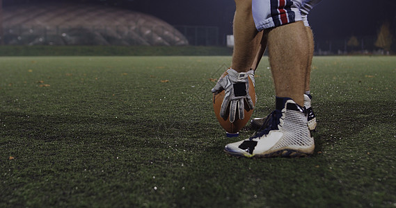 美国足球运动员准备夜间球场进行足球开球特写镜头图片