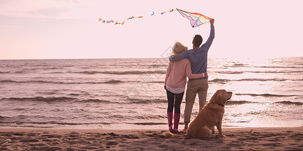 Autmun的天,夫妇海滩上跑步,用狗牵着手图片
