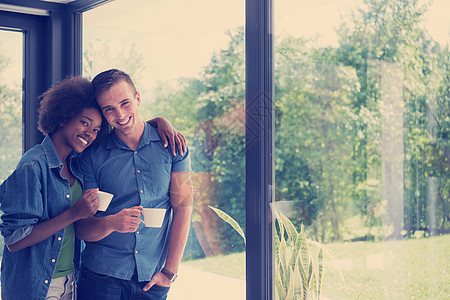 浪漫快乐的轻多民族夫妇他们豪华的家的窗边享受早晨的咖啡图片