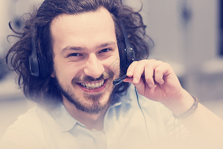 轻微笑的男呼叫中心接线员用耳机他的工作图片