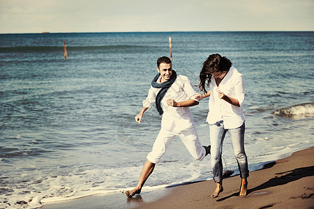 野外跑步穿着白色衣服的快乐轻夫妇美丽的海滩度假时浪漫的娱乐活动乐趣背景