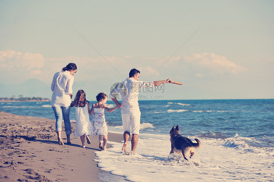幸福的家庭与宠物在美丽的海滩度假图片