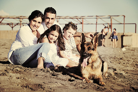 穿着白色衣服的快乐的轻家庭美丽的海滩度假时漂亮的狗玩图片