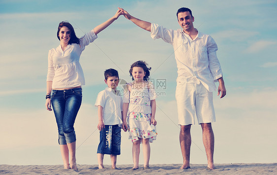 快乐的轻家庭海滩上玩得很开心,保护孩子的同时,用连接的手展示家庭标志图片