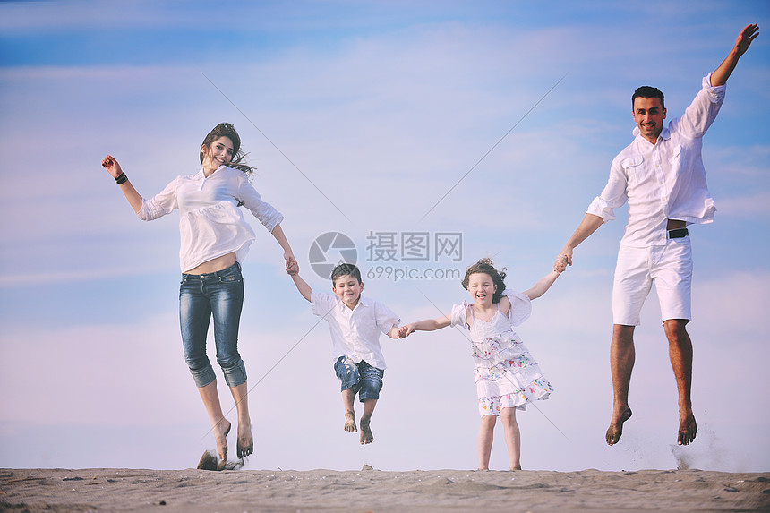 快乐的轻家庭海滩上玩得很开心,保护孩子的同时,用连接的手展示家庭标志图片