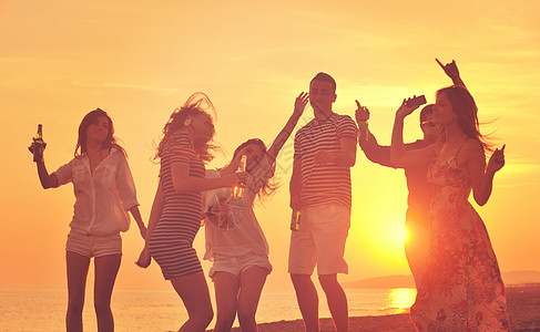 海滩聚会群轻人美丽的日落海滩上享受夏天的聚会背景