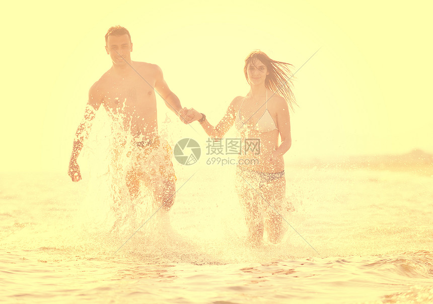 幸福的轻夫妇日落时海滩上度过浪漫的时光图片