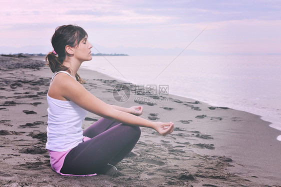 轻的女人清晨海滩上的莲花正丁冥想瑜伽图片