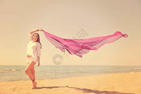 美丽的轻女人海滩上戴着围巾,放松微笑,玩得开心图片