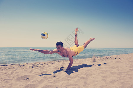 男子沙滩排球比赛运动员跳热沙上图片