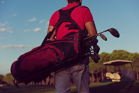 高尔夫球手背部,同时携带高尔夫球袋,并球场上步行下个洞步行携带高尔夫球袋时高尔夫球手的背部图片