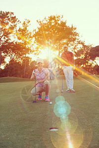 幸福的轻夫妇高尔夫球场上的肖像,背景美丽的日落日落时高尔夫球场上的情侣图片