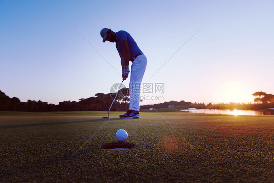 高尔夫球手击球与司机高尔夫球场美丽的日落背景高尔夫球手高尔夫球场击球图片