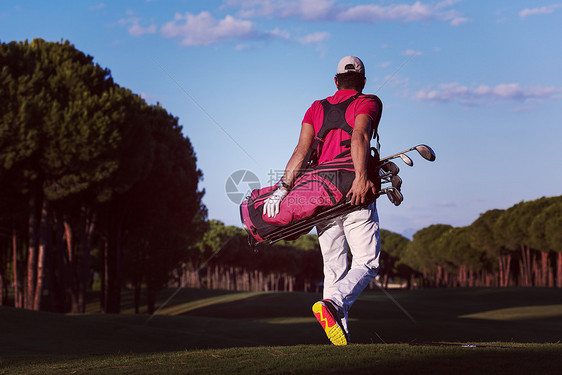 英俊的中东高尔夫球手背着高尔夫球袋,球场上走下个洞高尔夫球手步行携带高尔夫球袋图片