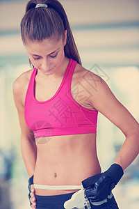 轻健康的女人健身馆的训练中测量腹部轻健康的女人测量腹部图片