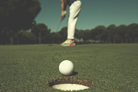 高尔夫球手击球与司机,球球场边缘的背景美丽的晴天高尔夫球手击球,球洞边背景图片