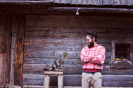 木屋前留着胡子猫的轻时髦男人的肖像人猫的肖像图片