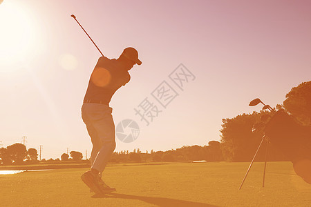 高尔夫球手击球与球杆美丽的早晨与太阳耀斑背景高尔夫球员击球图片