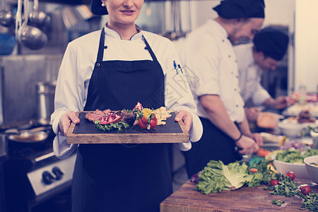 酒店餐厅厨房的女厨师着烤牛排盘蔬菜装饰女厨师着牛排盘图片
