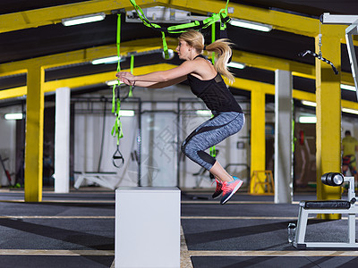 女人健身箱上跳出来轻的运动女子训练跳跃健身箱交叉健身健身房图片