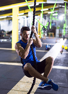 轻的肌肉男交叉健身健身房绳索攀岩绳索攀爬的人图片
